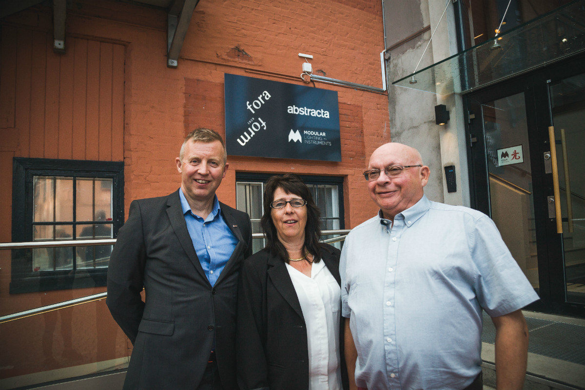 Forbundsleder i Industri Energi Frode Alfheim sammen med hovedtillitsvalgt i Fora Form Runa Busch og Paul Vatnebakk som har vært medlem i over 40 år, foran den nye logoen til Fora Form. Foto: Rikke Jeppson.